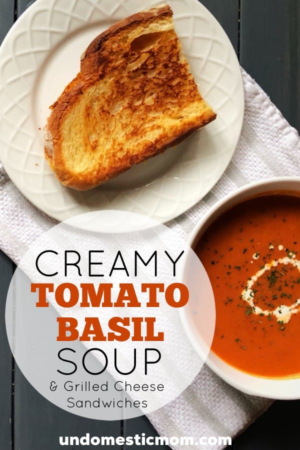 Creamy tomato basil soup next to a grilled cheese sandwich