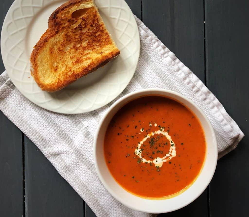 grilled cheese next to a bowl of creamy tomato basil soup