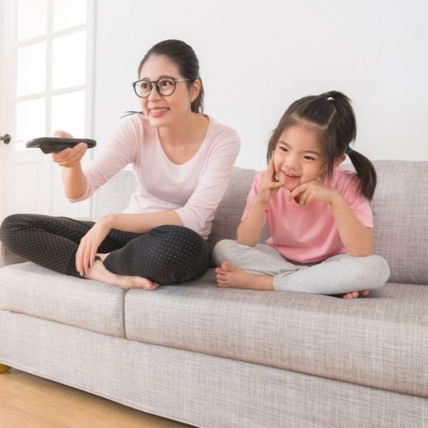 a mom and daughter watching fun television sitting on a couch