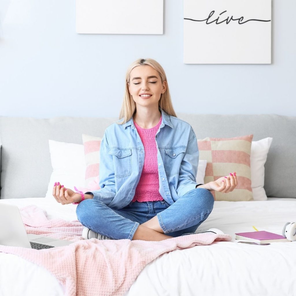 blonde woman meditating on a bed