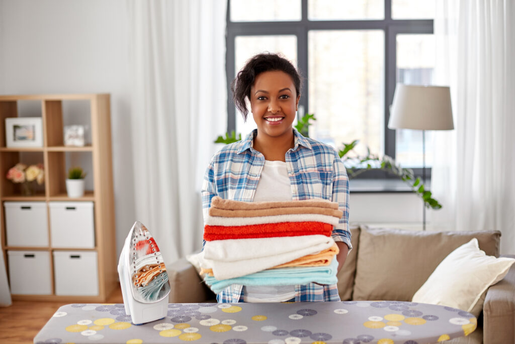 happy african american woman with ironed linen and iron board doing the best jobs for stay at home moms with no experience