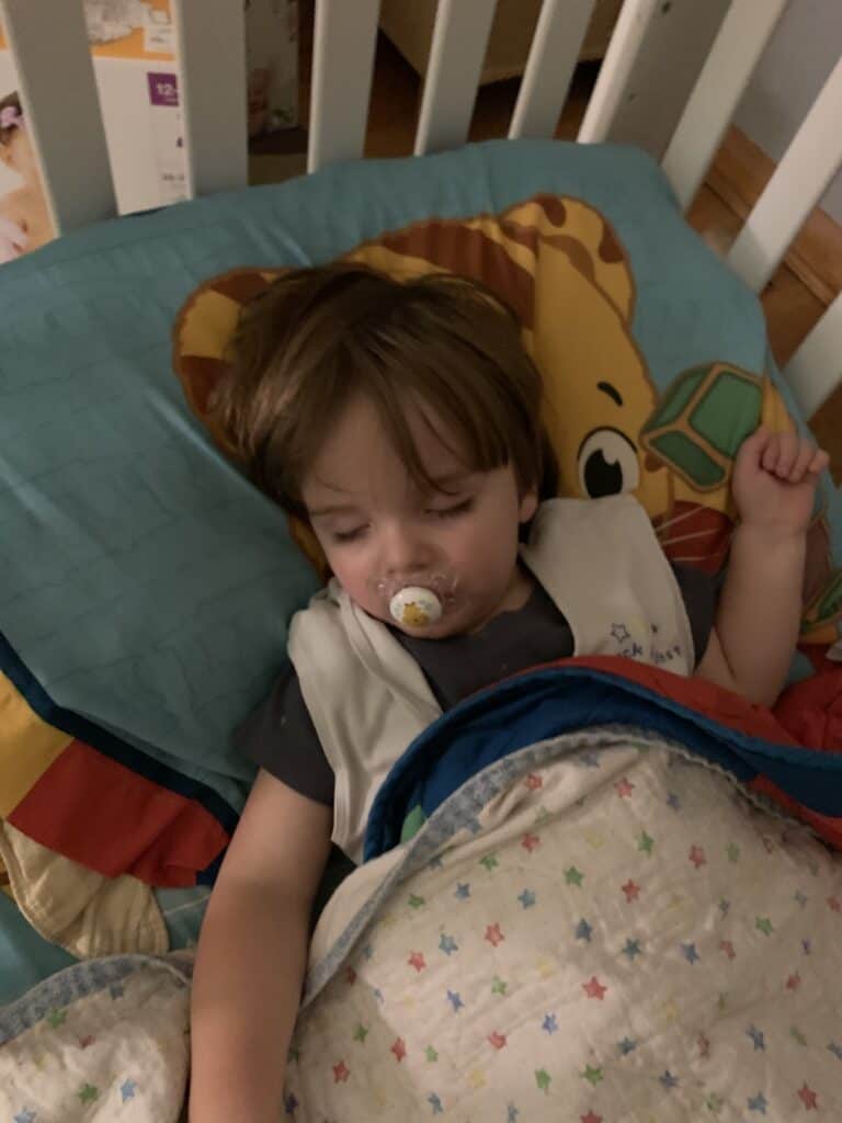 toddler boy sleeping in crib with a binky 