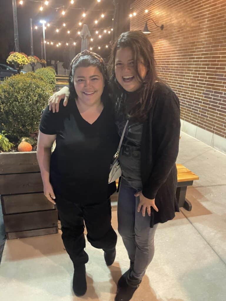 two brunette woman wearing all black at a birthday party posing for a picture